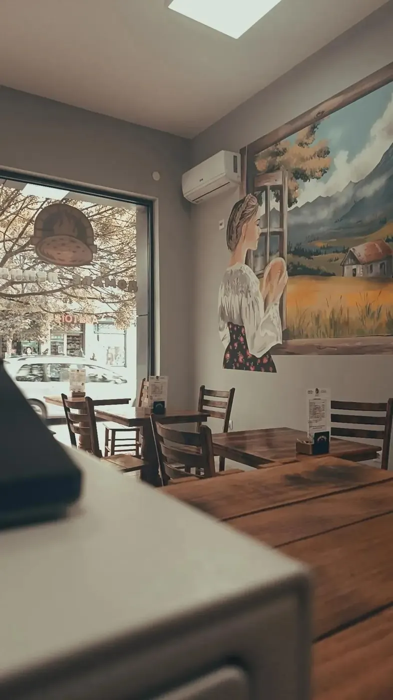 Enterijer radnje sa drvenim stolicama i muralom